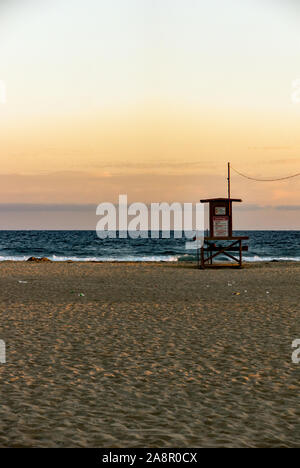 Newport, Kalifornien/USA - vom 18. Juli 2019: Ein roter Himmel bei Sonnenuntergang über dem Pazifischen Ozean und eine einsame Palme am Newport Beach in Kalifornien. Die lifeguar Stockfoto