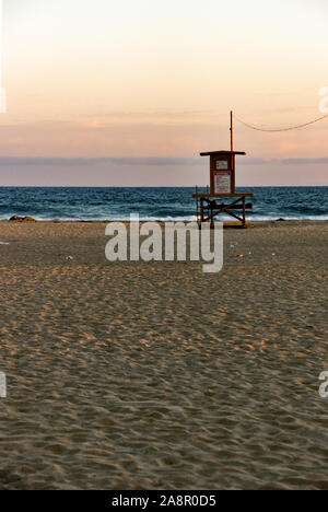 Newport, Kalifornien/USA - vom 18. Juli 2019: Ein roter Himmel bei Sonnenuntergang über dem Pazifischen Ozean und eine einsame Palme am Newport Beach in Kalifornien. Die lifeguar Stockfoto