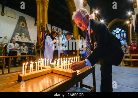 Beaminster, Dorset, Großbritannien. 10. November 2019. Vorsitzender des Beaminster Royal British Legion Tony Greenham Orte eines von 52 Leuchten in einem Holzkreuz, das alle Soldaten aus Beaminster in Dorset, die ihr Leben verloren, während im Zweiten Weltkrieg 1. und 2. Weltkrieg während der Städte in der Erinnerung Sonntag Service stellen Kerze. Foto: Graham Jagd-/Alamy leben Nachrichten Stockfoto