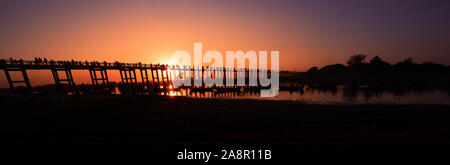 Silhouetten der Tourist in Boote und auf Brücke bewundern U-Bein Brücke über den Taungthaman See bei Sonnenuntergang in Amarapura. Mandalay, Myanmar Stockfoto