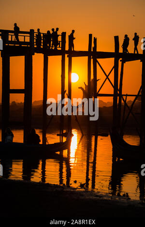 Silhouetten der Tourist in Boote und auf Brücke bewundern U-Bein Brücke über den Taungthaman See bei Sonnenuntergang in Amarapura. Mandalay, Myanmar Stockfoto