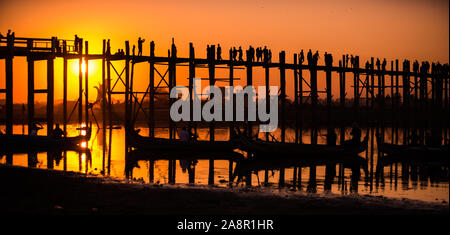 Silhouetten der Tourist in Boote und auf Brücke bewundern U-Bein Brücke über den Taungthaman See bei Sonnenuntergang in Amarapura. Mandalay, Myanmar Stockfoto