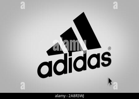 Logo der öffentlichen Unternehmen Adidas auf einem Bildschirm in der Nähe angezeigt. Credit: PIXDUCE Stockfoto