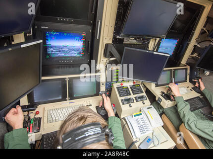 Piloten Ansehen in der Flugzeughalle an RAF Waddington in Lincolnshire, wo Piloten hinter Banken von Bildschirmen in einer Luft sitzt in der Fahrerkabine, verwenden Sie Sat-links unbemannte "Reaper" Drohnen fliegen fast konstante bewaffneten Aufklärungsmissionen über den Irak und Syrien zu steuern. November 2015 Stockfoto