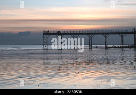 Historischen Pier in Bognor Regis West Sussex mit einem wunderschönen Sonnenuntergang hinter und Reflexionen auf dem Sand bei Ebbe. Stockfoto