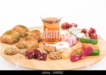 Holzbrett mit leckeren türkischen Süßigkeiten und Tee isoliert auf weißem Stockfoto