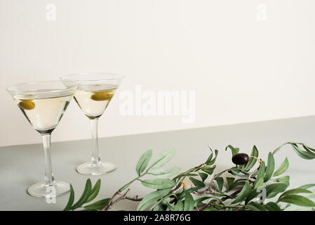 Zwei Gläser mit Cocktails und Olive Branch auf graue Oberfläche isoliert auf weißem Stockfoto
