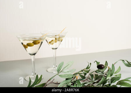 Cocktails in Martini Gläser mit Olive Branch auf graue Oberfläche, isoliert auf weißem Stockfoto