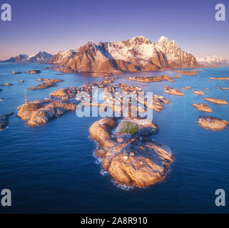 Luftaufnahme von Felsen im Meer, schneebedeckte Berge, purple sky Stockfoto