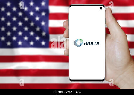 Logo der öffentlichen Amcor plc angezeigt auf einem Smartphone. Flagge der USA Hintergrund. Credit: PIXDUCE Stockfoto