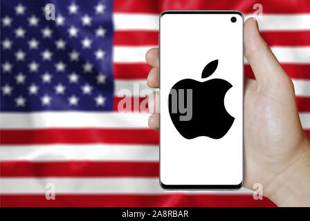 Logo der Firma Apple Inc. auf dem Smartphone angezeigt. Flagge der USA Hintergrund. Credit: PIXDUCE Stockfoto