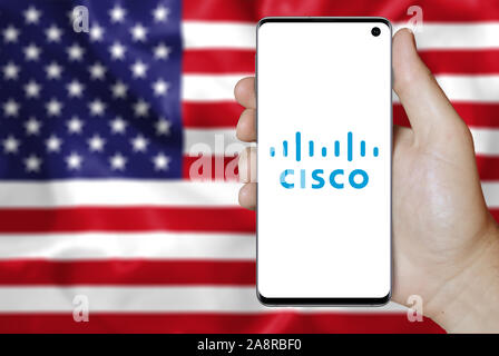 Logo der öffentlichen Unternehmen Cisco Systems auf dem Smartphone angezeigt. Flagge der USA Hintergrund. Credit: PIXDUCE Stockfoto