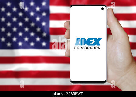 Logo der öffentlichen Unternehmen IDEX Corporation auf dem Smartphone angezeigt. Flagge der USA Hintergrund. Credit: PIXDUCE Stockfoto