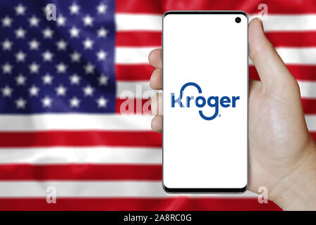 Logo der öffentlichen Unternehmen Kroger Co. auf dem Smartphone angezeigt. Flagge der USA Hintergrund. Credit: PIXDUCE Stockfoto