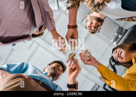 Ansicht von unten auf das fröhliche Geschäftsleute und multikulturellen Geschäftsfrauen toasten Champagner Gläser im Büro Stockfoto