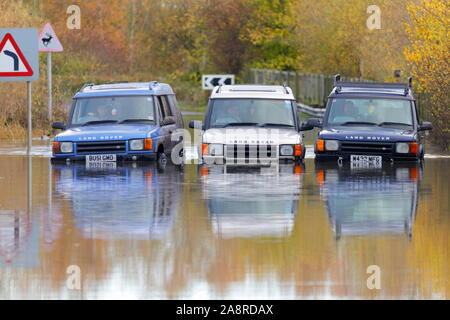 Landrover discoverys aufgereiht auf eine überschwemmte Straße bei Fairburn Ings in der Nähe Castleford in West Yorkshire Stockfoto