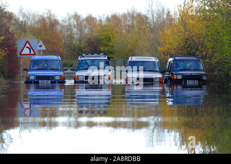 Landrover discoverys aufgereiht auf eine überschwemmte Straße bei Fairburn Ings in der Nähe Castleford in West Yorkshire Stockfoto