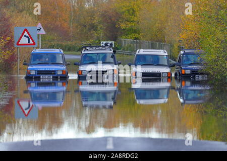 Landrover discoverys aufgereiht auf eine überschwemmte Straße bei Fairburn Ings in der Nähe Castleford in West Yorkshire Stockfoto