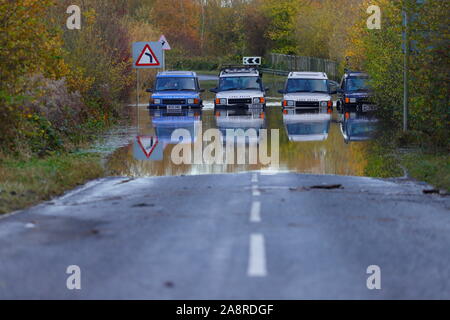 Landrover discoverys aufgereiht auf eine überschwemmte Straße bei Fairburn Ings in der Nähe Castleford in West Yorkshire Stockfoto