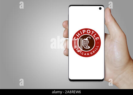 Logo der öffentlichen Unternehmen Chipotle Mexican Grill angezeigt auf einem Smartphone. Grauer Hintergrund. Credit: PIXDUCE Stockfoto