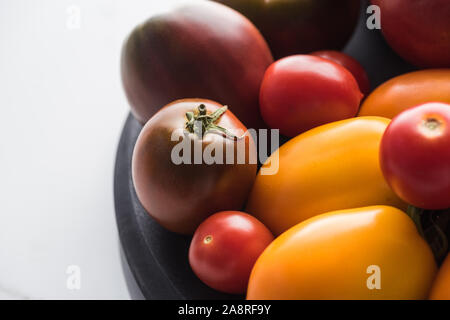 Nahaufnahme von roten und gelben Tomaten auf hölzernen pizza Pan auf Marmor Oberfläche Stockfoto