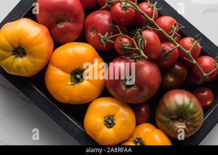 Blick von oben auf die Tomaten in Holz- black box auf Marmor Oberfläche Stockfoto