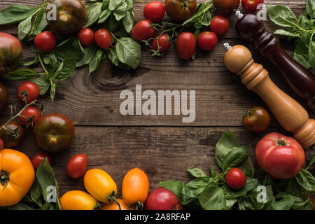 Blick von oben auf die Tomaten, Spinat, Pfeffermühle, salzmühle und leeren Raum in der Mitte auf hölzernen Tisch Stockfoto