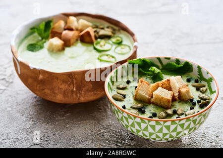 Schalen mit leckeren grünes Gemüse cremige Suppe mit Croutons, Jalapenos, schwarzer Pfeffer und Kürbiskerne Stockfoto