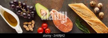 Panorama-aufnahme des rohen Lachs Steak in der Nähe von Gemüse, Traube, Wachtel Eier, Erdnüsse, Baguette und Olivenöl auf Marmor Oberfläche Stockfoto