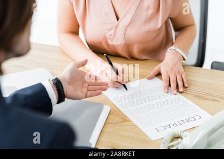 7/8-Ansicht von Geschäftsleuten unterzeichnen Vertrag im Büro Stockfoto