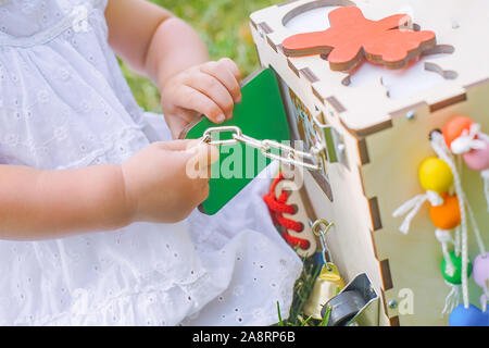 Das Kind spielt eine busiboard. Ein Mädchen öffnet die Tür eines entwicklungspolitischen Spielzeug. Stockfoto