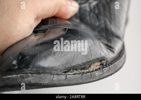 Der alte Frauen Stiefel mit seitlichen Beschädigung von echtem Leder zu imitieren, einem Krokodil Muster. Stockfoto