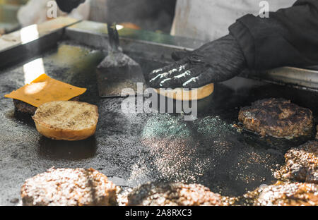Küchenchefs an einem Street Food Markt braten Rindfleisch Fleischpflanzerl mit Käse. Stockfoto