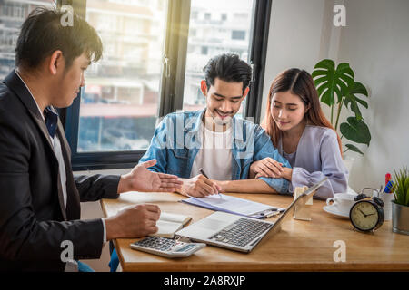 Asiatische junge Paar Zeichen Kontakt von Haus in Kauf oder Miete, haben Vertriebsmitarbeiter bieten den Zustand im Dokument auf der Arbeitsfläche Tabelle Stockfoto