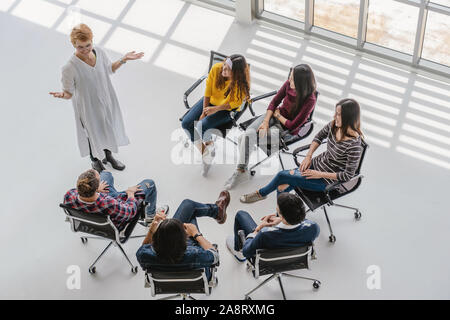 Blick von oben auf die asiatischen Senior Manager Frau präsentieren die kreativen Ideen vor der Gruppe der Asiatischen und multiethnische Geschäftsleute mit lässiger Anzug in ha Stockfoto