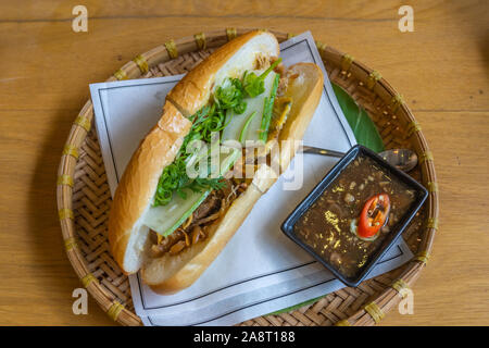 Köstliche vietnamesische Huhn banh mi serviert auf traditionellen rattan Fach Stockfoto