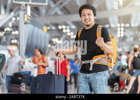 Portrait von asiatischen reisenden mit Gepäck mit reisepass stehen über den Flug für den Check-in am Flight Information Display im modernen eine FLUGHAF Stockfoto