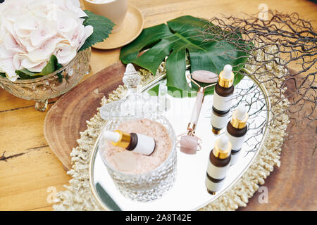 Kleine Flaschen mit Wesen und die Emulsion und Quarz Gesicht Walze auf Metall Tablett im Beauty Salon Stockfoto