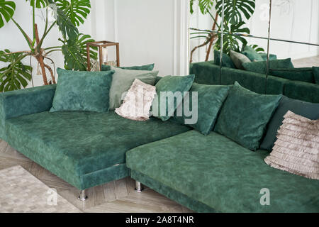 Sofa mit Kissen, Smaragd Farbe. Luxus Zimmer mit Parkettböden, Kamin, Sofa und Zimmerpflanze. Stuck an den Wänden Stockfoto