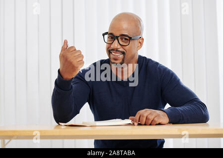 Portrait von Happy reifer Mann lächelnd beim Befüllen planner auf seinem Tisch Stockfoto
