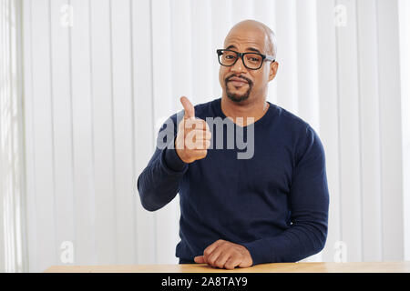 Positive Geschäftsmann lächelnd und mit Daumen hoch, wenn im Büro Schreibtisch sitzen Stockfoto
