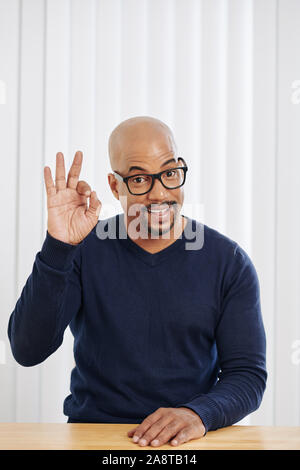 Portrait von positiven Geschäftsmann in Gläsern mit ok Zeichen und Kamera Stockfoto