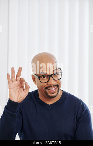 Gerne schön gemischt - Rennen Mann in Gläser mit ok Zeichen und lächelnd an Kamera Stockfoto