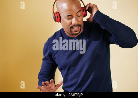 Positiver Mann in Kopfhörern hören seines Lieblings Musik und Tanz Stockfoto
