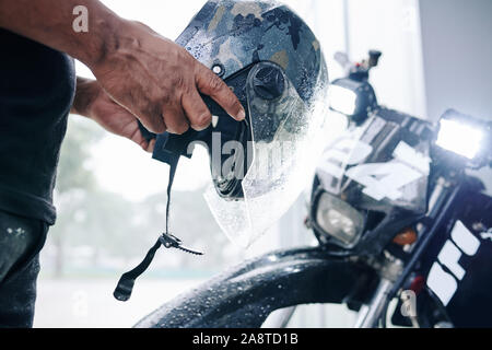 Hände von motorradfahrer auf Helm vor der Fahrt in die Stadt Stockfoto