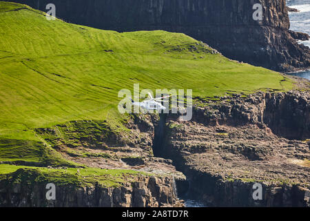 Hubschrauber fliegen über mykines atlantic Klippen in Färöer Inseln. Dänemark Stockfoto