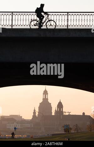 Dresden, Deutschland. 11 Nov, 2019. Bei Sonnenaufgang, ein Radfahrer kreuzt die Marienbrücke Brücke vor der Kulisse der Altstadt und zeichnet sich als Silhouette. Credit: Sebastian Kahnert/dpa-Zentralbild/dpa/Alamy leben Nachrichten Stockfoto