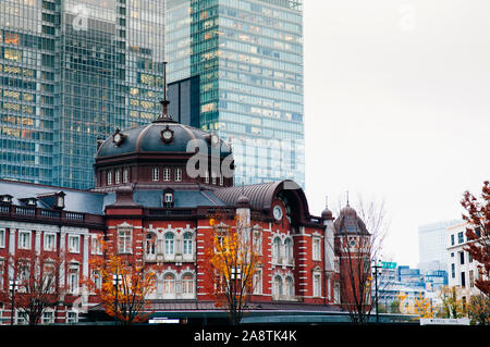 DEC 6, 2019 Tokyo, Japan - Tokyo Station alten denkmalgeschützten Gebäude Marunouchi Bezirk mit modernen Büro Turm im Hintergrund Stockfoto