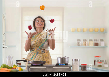 Die Frau in der Küche jonglieren capsicums Stockfoto