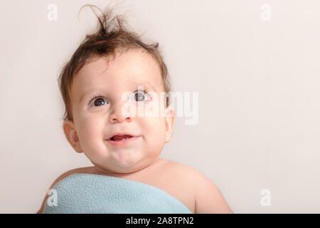 Ein 9 Monate altes Baby mit 2 Zähnen lächelnd und sah in eine blaue Decke abgedeckt Stockfoto